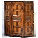 An early 20th century reproduction three-door carved and panelled shaped hall robe with cast iron