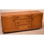 A 1960s Ercol light elm sideboard, three central drawers flanked by two cupboard doors, on castors,