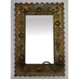 An Arts and Crafts rectangular mirror in brass frame with beaten floral and fruit decoration,
