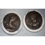 A pair of oval marble-effect plaques with Art Nouveau raised metal decoration of young females,