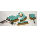 A George V seven-piece enamelled dressing table set, comprising eight-day clock, two hand brushes,