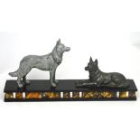 An Art Deco style figural group of two German Shepherd dogs; one standing, the other sitting,