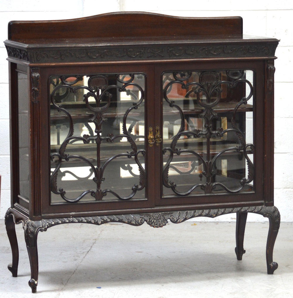 An Edwardian mahogany display cabinet with ornate carved woodwork to twin glass doors,