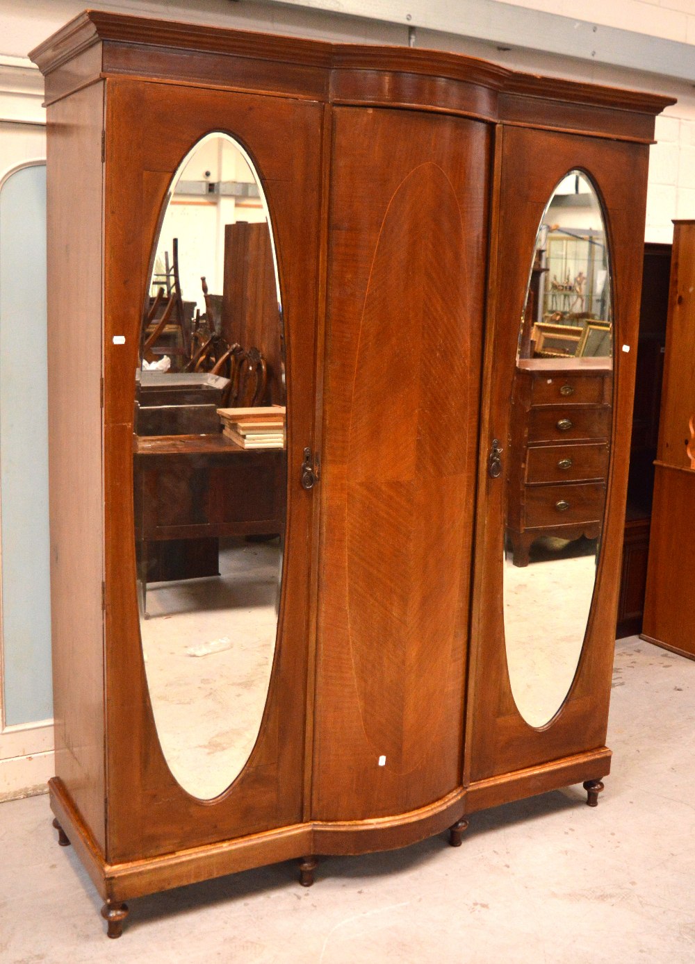 An Edwardian mahogany inlaid triple-door wardrobe with central bow-front panel and two mirrored