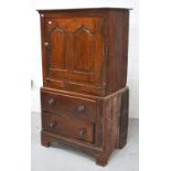 An antique oak cupboard, the upper section with arched panel door above two drawers on bracket feet,