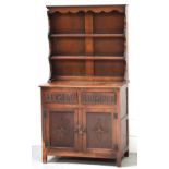 A carved oak Welsh dresser, two-shelf panel plate rack, two short drawers over two cupboard doors,