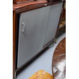 A 1950s/60s teak-cased cabinet with grey sliding vinyl covered doors, interior shelves,