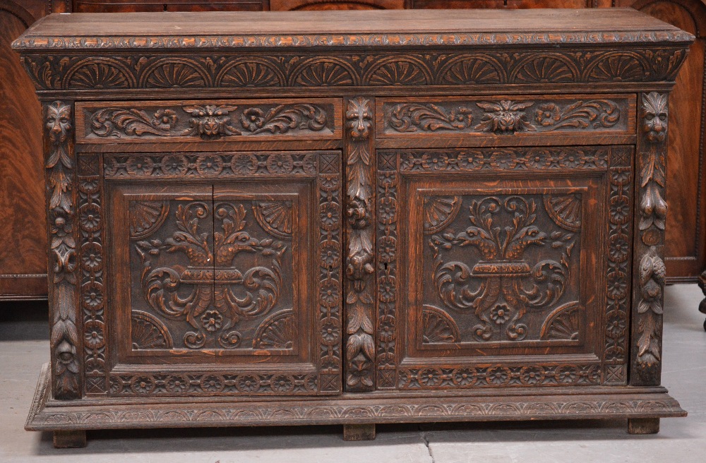 A late Victorian carved oak sideboard, two short drawers over two cupboard doors,