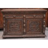 A late Victorian carved oak sideboard, two short drawers over two cupboard doors,