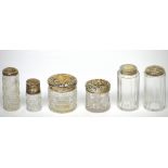 Six cut glass silver-topped vanity bottles to include a Victorian faceted vanity jar, London 1886,