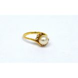 An 18ct gold ladies' dress ring set with single pearl on a twist with three small diamonds to