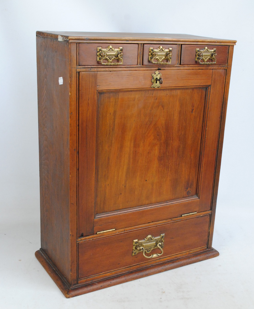 A pine table cabinet with three short drawers above a hinged fall-front and a single full length