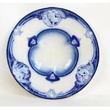 An Art Nouveau style blue and white porcelain circular dish with trilobed centre within cherubic