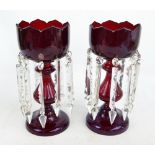 A pair of Victorian ruby glass table lustres with clear glass prisms, shaped top and circular foot,