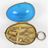 An early 20th century gilt base metal sewing set in blue frost glass egg shaped case on suspension