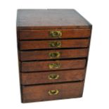 An early 20th century oak collectors' cabinet with six graduated drawers and lacquered campaign