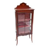 An Edwardian mahogany and inlaid display cabinet with shaped back above single glazed door