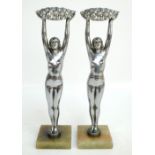 A pair of Art Deco chromed figures of nude females, each holding a basket of flowers aloft,