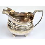 A George III hallmarked silver cream jug of oval form with cast rim and floral pin pricked