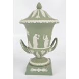 WEDGWOOD; a green jasperware campana vase and cover with raised handles to lower part,