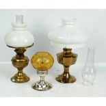 A brass oil lamp with circular base, brass reservoir, opaque white shade and chimney,