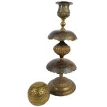 A decorative Eastern metal candlestick with bell shaped sconce above an incised ornamental