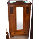 An Edwardian walnut mirror-door wardrobe with broken swan neck pediment above carved panels to