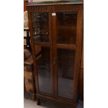 A reproduction oak two-door display cabinet in the Priory style, with bevelled glass, three shelves,