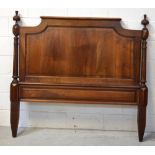 An early 20th century mahogany headboard, panelled with carved finials and tapering columns,