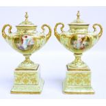 A pair of Vienna style porcelain oval twin handled footed urns with covers,