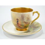 A Royal Worcester cup and saucer hand painted by James Stinton and decorated with pheasants in a