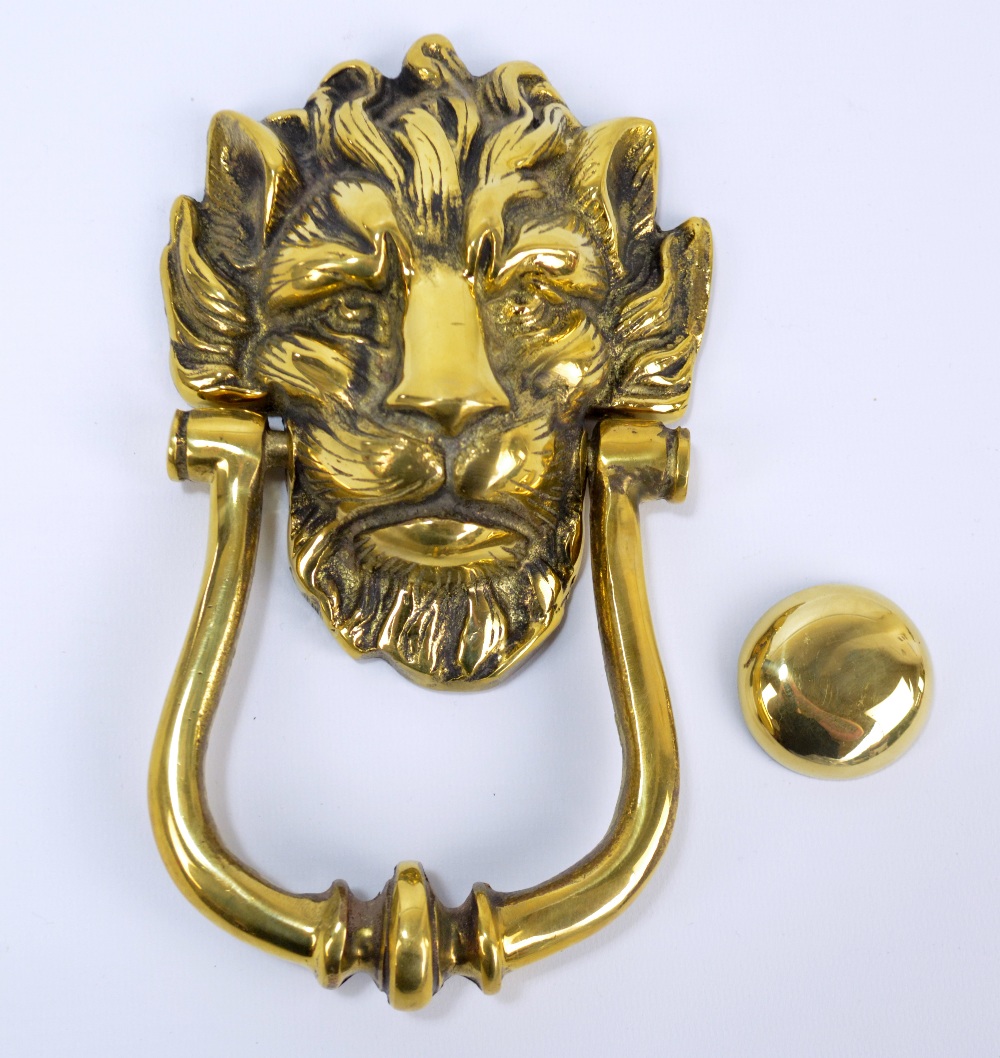 A large decorative brass door knocker in the form of a lion head mask,