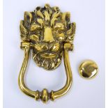 A large decorative brass door knocker in the form of a lion head mask,