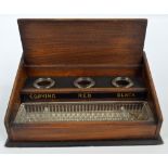 An early 20th century oak slide top ink stand enclosing three clear glass ink bottles and pen tray.