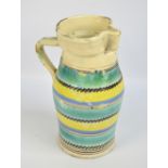 A large late 19th century rustic creamware jug painted with horizontal bands of green, yellow,