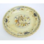 A late 18th century continental tin glazed charger decorated with abstract floral sprays to the