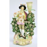 An 18th century Derby figural candlestick modelled as a young gentleman wearing elaborate clothes
