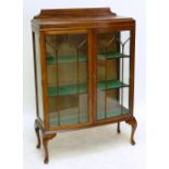 An early 20th century oak bowfronted glazed display cabinet raised on cabriole legs.