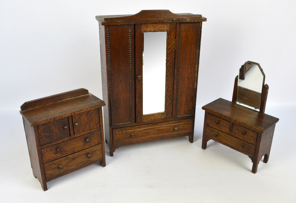 An early 20th century miniature oak three piece bedroom suite comprising a mirrored wardrobe,