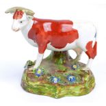 An early 19th century Walton type Staffordshire pearlware figure of a standing cow on floral