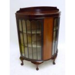 An early 20th century mahogany bowfronted display cabinet with pair of glazed doors enclosing three