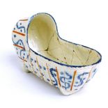 A late 18th century Prattware cradle decorated in shades of ochra and blue on an incised ground,