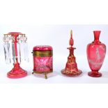 Four pieces of cranberry glass comprising a Mary Gregory over painted baluster vase,