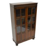 An early 20th century oak bookcase with a pair of glazed doors above linen fold panels,