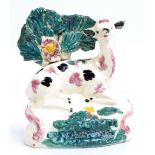A late 19th century Staffordshire figure of a reclining deer with leaf moulded section behind and