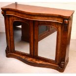 A Victorian serpentine-topped chiffonier with frieze drawer over pair of doors with arched mirrored