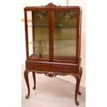 An Edwardian walnut display cabinet with pair of glazed doors enclosing glass shelves,