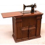 A late 19th/early 20th century mahogany sewing cabinet with integrated treadle Singer sewing