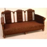 A late 19th century oak sofa daybed with three button-back panelled seat backs, brown upholstery,