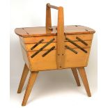 A mid-20th century teak metamorphic sewing box raised on four splayed supports.